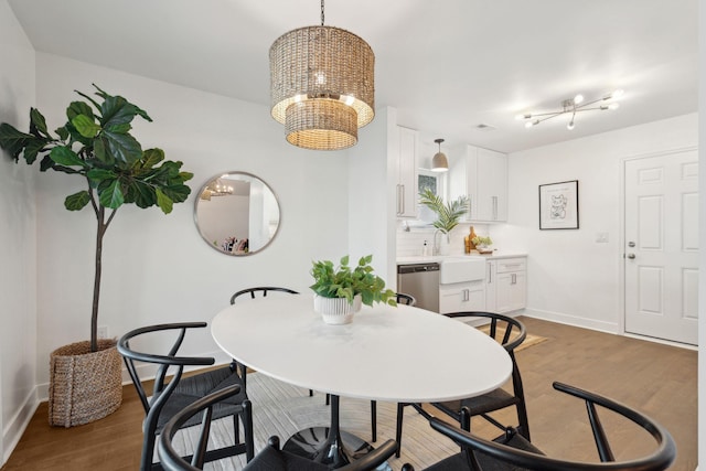 dining area with sink, an inviting chandelier, and dark hardwood / wood-style flooring