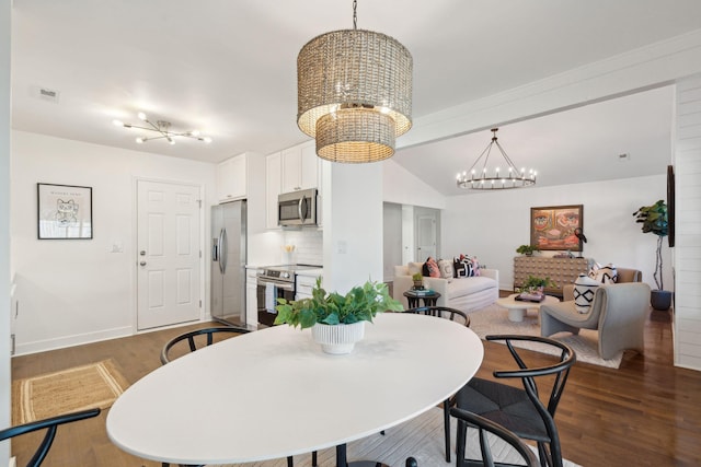 dining space with dark wood-type flooring, a chandelier, and vaulted ceiling