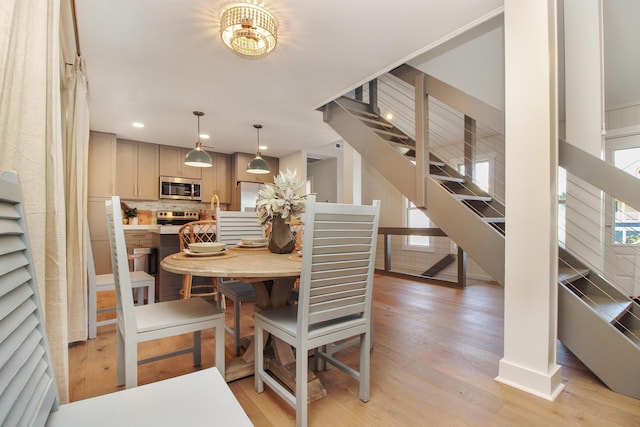 dining room with recessed lighting, light wood-style flooring, and stairs