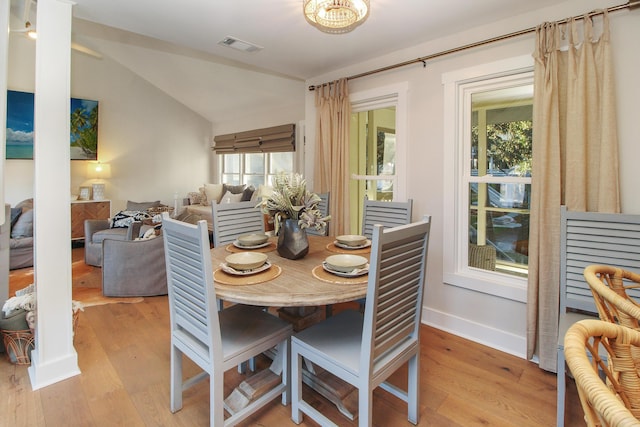 dining area with baseboards, visible vents, vaulted ceiling, and light wood finished floors