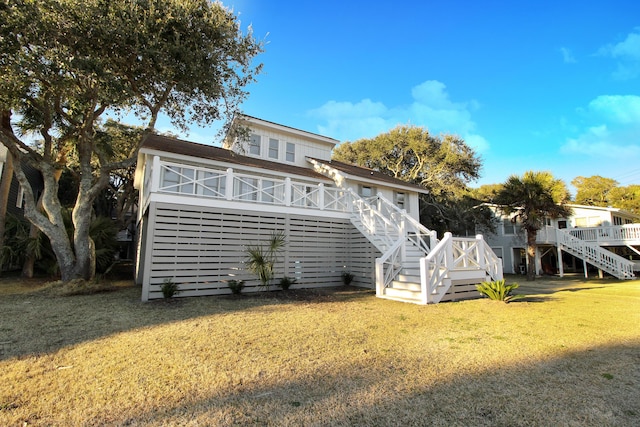 rear view of property featuring a lawn, a wooden deck, and stairs