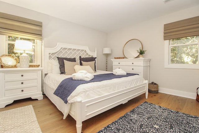 bedroom featuring visible vents, baseboards, and wood finished floors