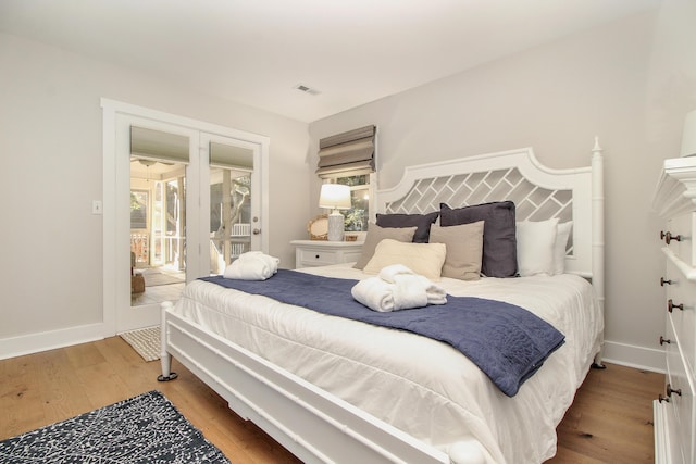 bedroom featuring access to exterior, wood finished floors, visible vents, and baseboards