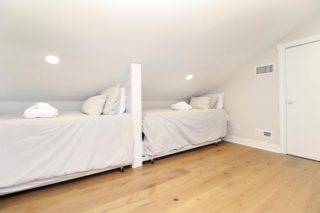 bedroom featuring vaulted ceiling, wood finished floors, visible vents, and baseboards