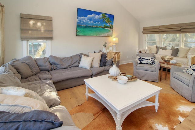 living room featuring light wood-style flooring, baseboards, and vaulted ceiling