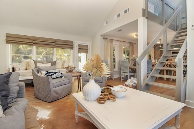 living room with high vaulted ceiling, stairway, wood finished floors, and visible vents