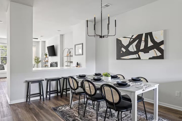 dining room featuring dark wood-type flooring, a chandelier, and baseboards
