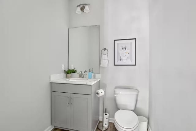 bathroom featuring baseboards, toilet, vanity, and wood finished floors