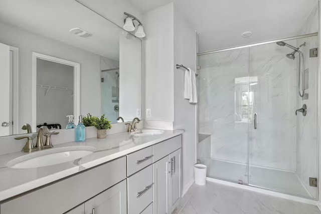 bathroom featuring a marble finish shower, double vanity, and a walk in closet