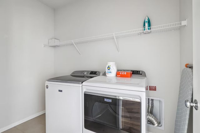 washroom with separate washer and dryer, baseboards, and light tile patterned flooring