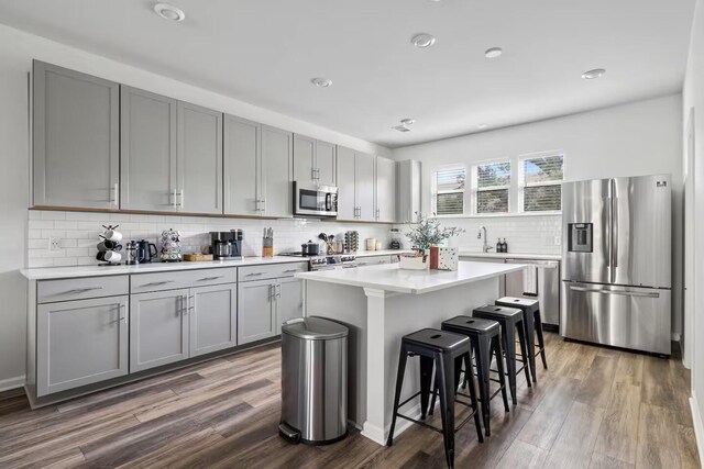 kitchen with stainless steel appliances, gray cabinetry, dark wood-style flooring, and recessed lighting