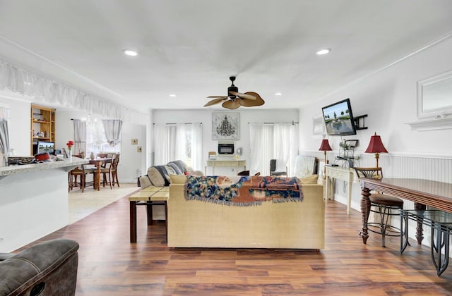 living room with recessed lighting, ceiling fan with notable chandelier, ornamental molding, and wood finished floors