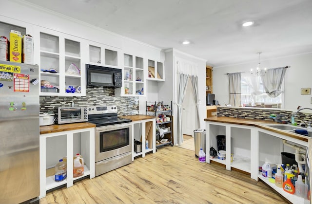 kitchen with a chandelier, butcher block countertops, appliances with stainless steel finishes, light wood-style floors, and a sink