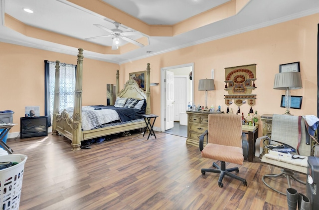 bedroom with crown molding, a tray ceiling, and wood finished floors