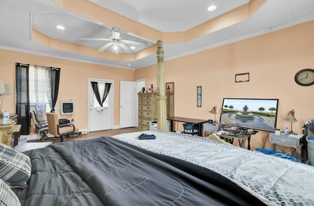 bedroom with heating unit, wood finished floors, recessed lighting, ornamental molding, and a raised ceiling