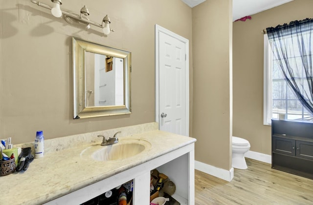 bathroom with baseboards, toilet, wood finished floors, and vanity