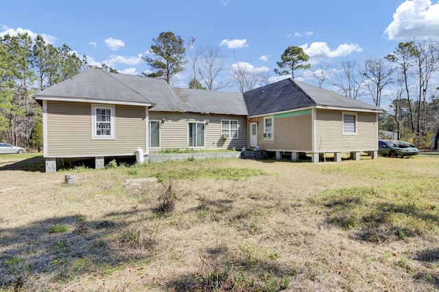 rear view of property featuring a lawn and a shingled roof