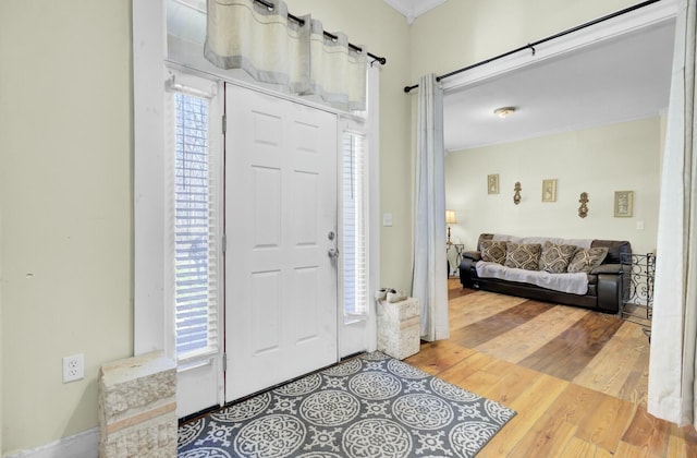 foyer featuring wood finished floors and ornamental molding