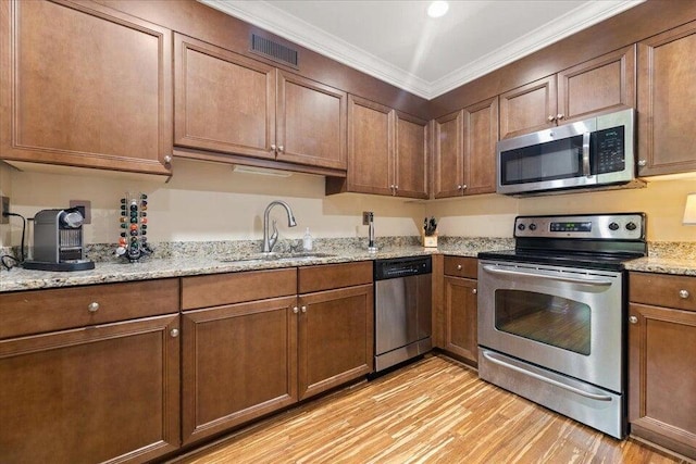 kitchen featuring sink, crown molding, stainless steel appliances, light stone countertops, and light hardwood / wood-style floors