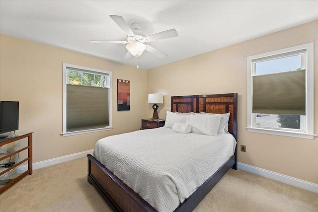 bedroom featuring light carpet, a ceiling fan, and baseboards