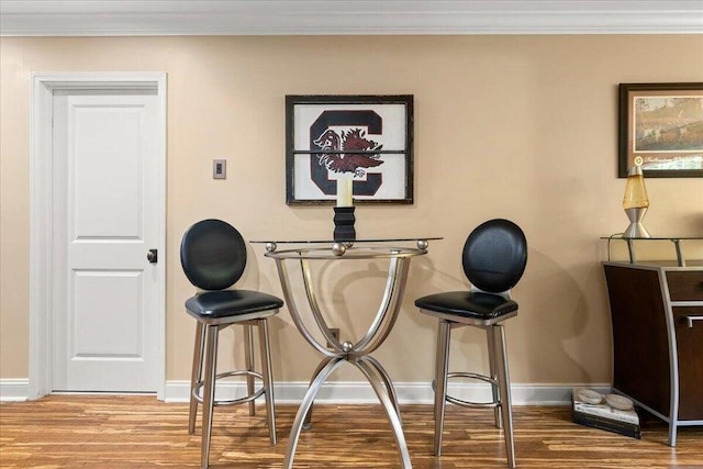 interior space featuring ornamental molding, wood finished floors, and baseboards