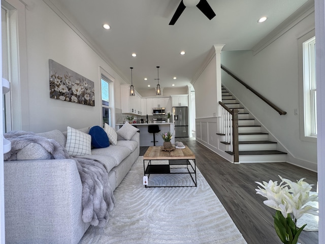 living room featuring stairway, recessed lighting, dark wood-type flooring, and ornamental molding