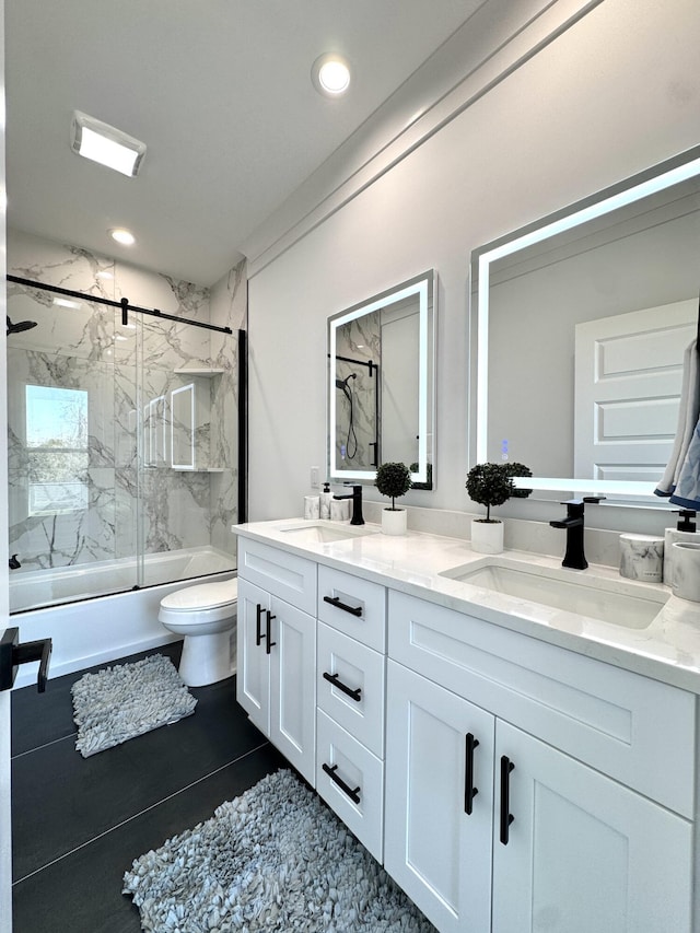 full bathroom with double vanity, toilet, shower / bath combination with glass door, and a sink