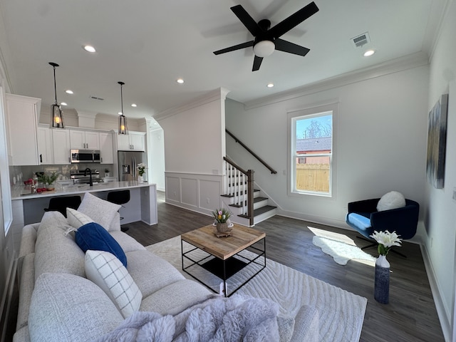 living area featuring dark wood-type flooring, stairway, visible vents, and ornamental molding