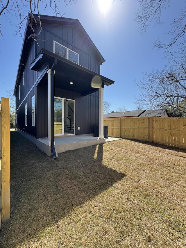 rear view of property with a patio area, a yard, fence, and board and batten siding