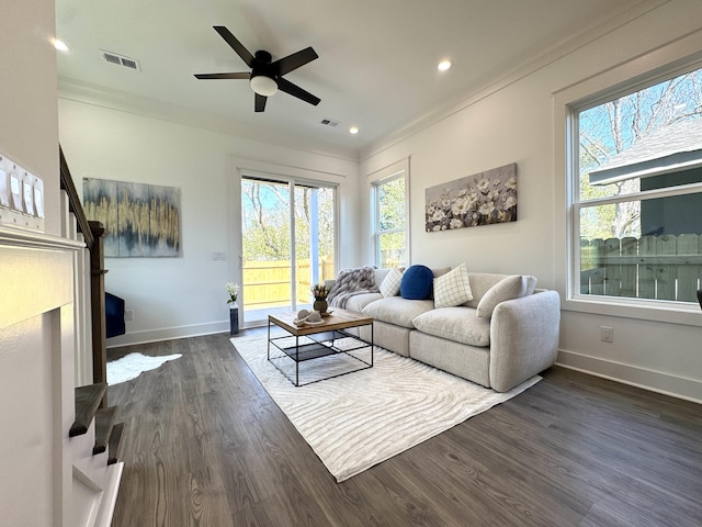 living room featuring dark wood finished floors, crown molding, baseboards, and visible vents