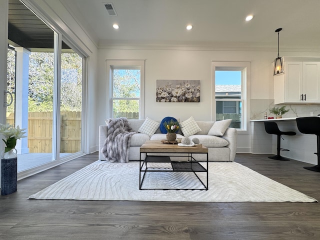 living area featuring dark wood-type flooring, recessed lighting, visible vents, and ornamental molding