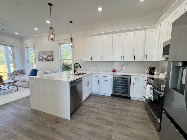 kitchen with beverage cooler, dark wood finished floors, decorative backsplash, appliances with stainless steel finishes, and a sink