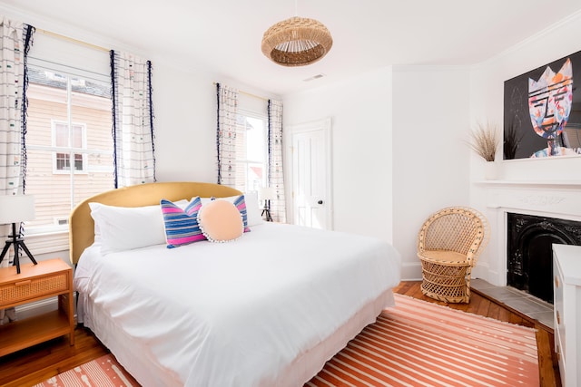 bedroom featuring wood-type flooring, crown molding, and multiple windows