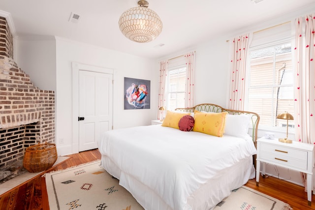 bedroom with a fireplace, light hardwood / wood-style flooring, and ornamental molding