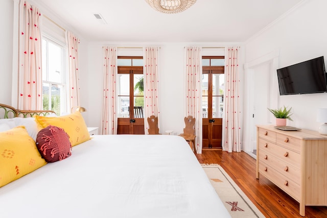 bedroom with access to outside, multiple windows, crown molding, and wood-type flooring