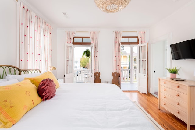 bedroom featuring access to exterior, light hardwood / wood-style flooring, multiple windows, and ornamental molding