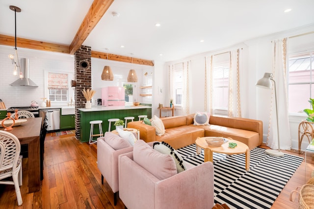 living room with beam ceiling, a wealth of natural light, hardwood / wood-style floors, and sink