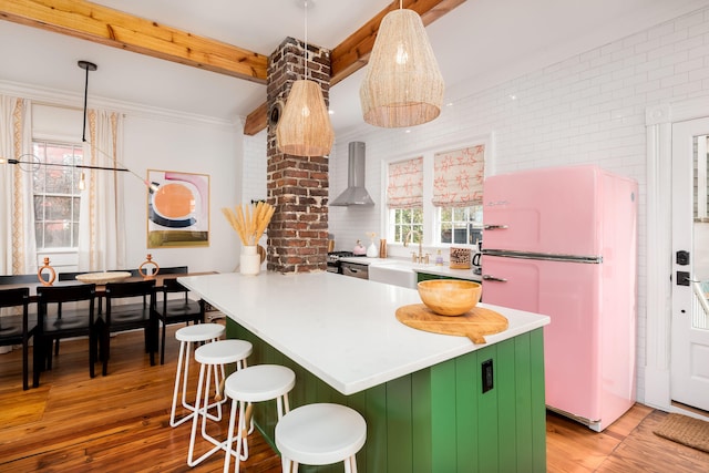 kitchen with sink, wall chimney range hood, beamed ceiling, white refrigerator, and light wood-type flooring