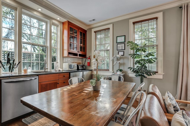 dining area with wood-type flooring, plenty of natural light, ornamental molding, and sink