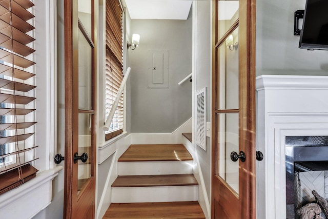 staircase featuring electric panel and hardwood / wood-style floors