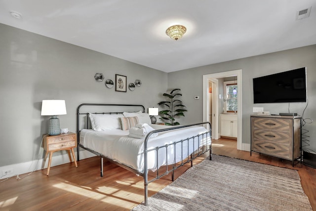 bedroom with connected bathroom and hardwood / wood-style floors