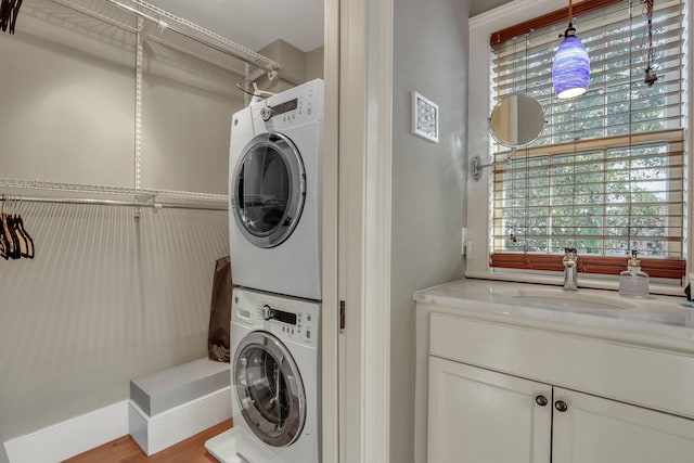 washroom with light hardwood / wood-style floors, sink, and stacked washer and clothes dryer