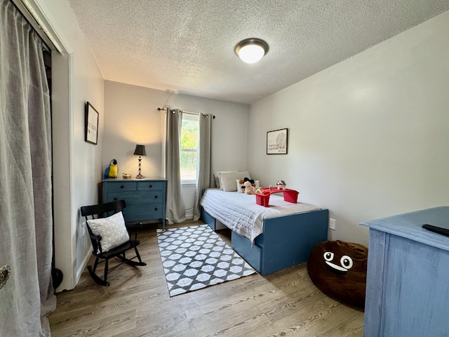 bedroom with a textured ceiling and wood finished floors