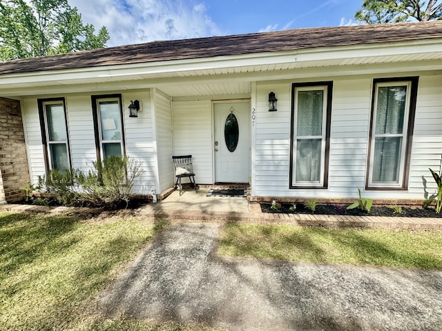 doorway to property with a porch and roof with shingles