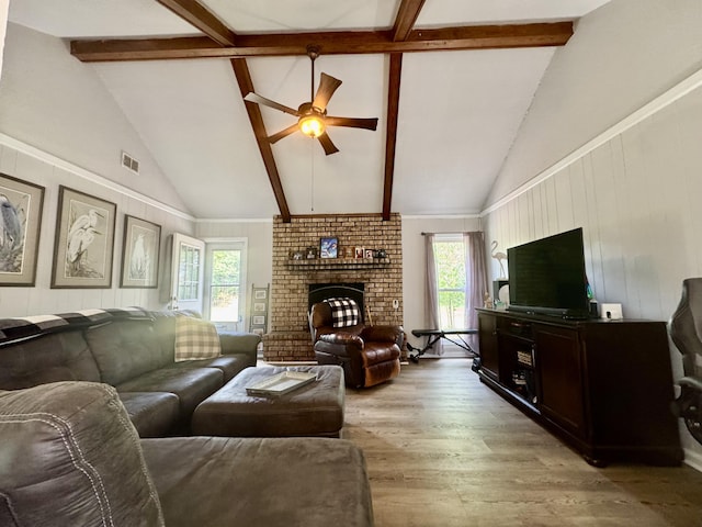 living room with light wood-style floors, a ceiling fan, beam ceiling, and a wealth of natural light