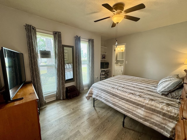 bedroom with a ceiling fan, a textured ceiling, and wood finished floors