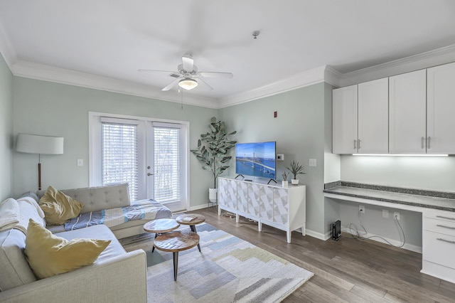 living room featuring crown molding, wood finished floors, built in desk, and baseboards