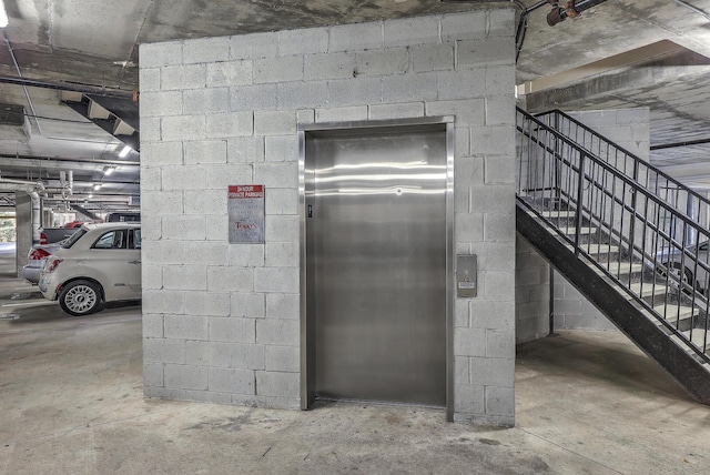 parking deck featuring elevator and concrete block wall