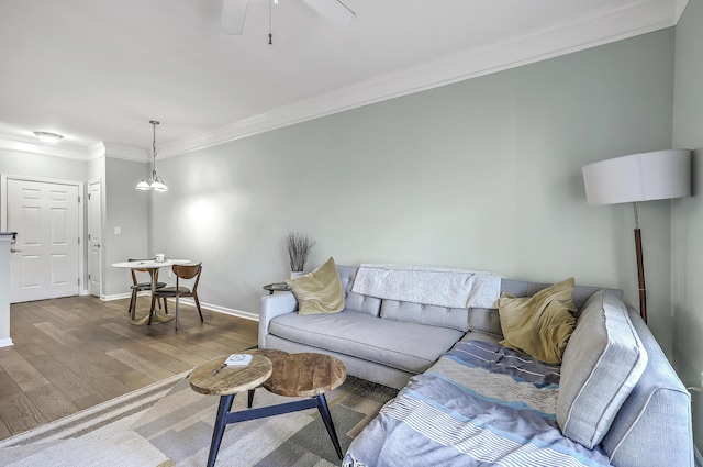 living room with baseboards, wood finished floors, ornamental molding, and a ceiling fan