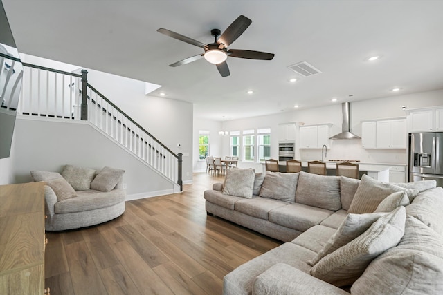 living room featuring wood finished floors, a ceiling fan, stairs, recessed lighting, and baseboards